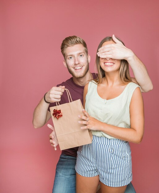 Der Mann, der ihre Freundinnen bedeckt, mustert beim Geben der Geschenkeinkaufstasche