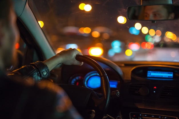 Der mann fährt ein modernes auto in der stadt. abend nachtzeit
