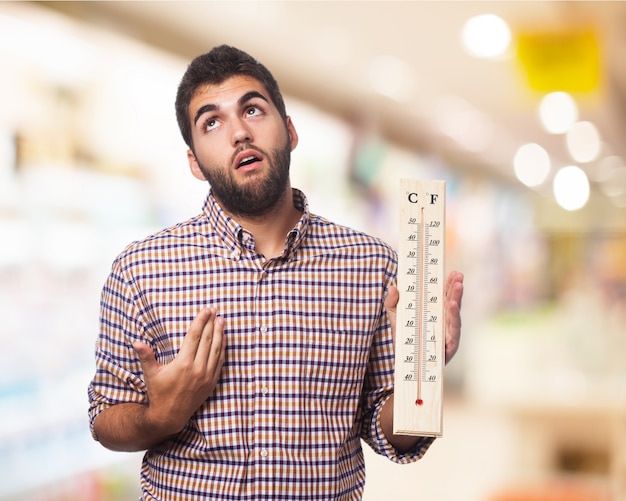 Der Mann mit einem großen Thermometer in einer Hand