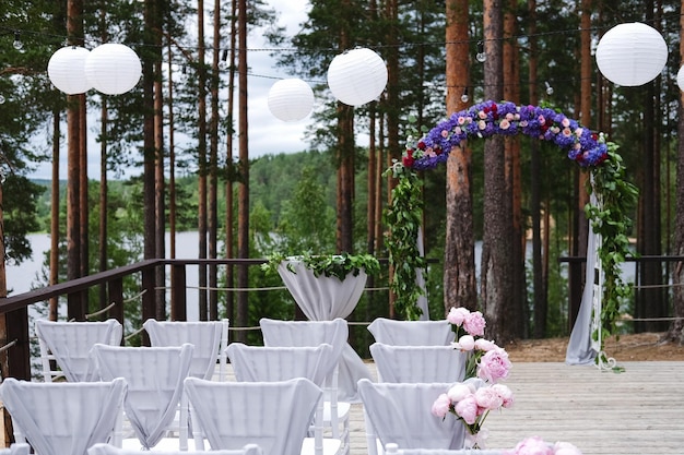 Der mit Stoffblumen und Grün geschmückte Bogen für die Hochzeitszeremonie befindet sich in einem Kiefernwald