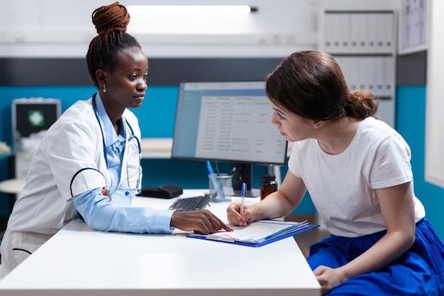 Der Patient unterschreibt nach der ärztlichen Untersuchung ein medizinisches Antragsformular für einen Anspruch auf eine Krankenversicherung für Notfallverletzungen. Gesundheitsspezialist unterstützt Frau bei der Erstellung eines Medicare-Richtliniendokuments