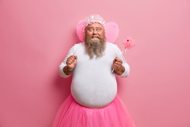 Der pralle bärtige Mann hat das Bild einer magischen Fee, ballt die Faust, freut sich über seine Fähigkeit, Dinge verschwinden zu lassen, gibt vor, ein übernatürliches Wesen zu sein, spielt mit Kindern auf der Party