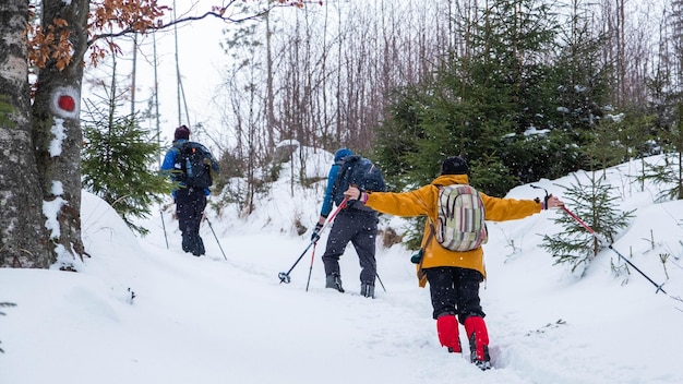 Der Rücken von erfahrenen freundlichen Wanderern mit knalligen Skianzügen und bunten Mützen