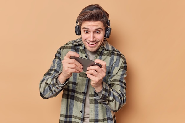 Der süchtige Mann spielt Videospiele, hält das Smartphone horizontal und versucht, ein schwieriges Level zu überwinden