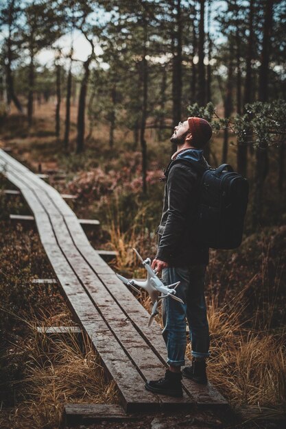 Der trendige bärtige Student genießt den Herbstspaziergang mit seiner Drohne im Park.