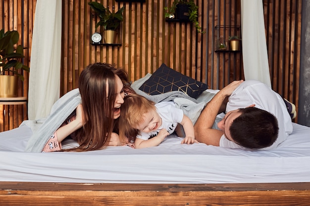 Der Vater, die Mutter und die Tochter liegen auf dem Bett