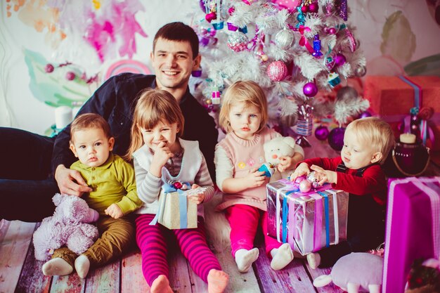 Der Vater umarmt seine Kinder in der Nähe von Weihnachtsbaum
