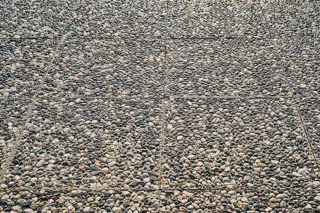 Der Weg ist mit Pflastersteinen aus Naturstein gepflastert. Selektiver Fokus auf Pflastersteinen. Idee für den Hintergrund und die Dekoration von städtischen Räumen