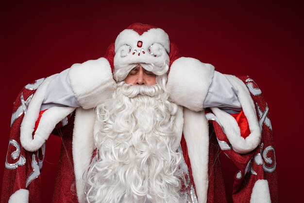 Der Weihnachtsmann wird müde und packt den Kopf für Kopfschmerzen, geschlossene Augen