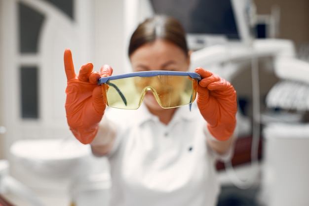 Der Zahnarzt bereitet sich auf den Empfang vor. Der Arzt hält seine Brille. Frau in Gummihandschuhen