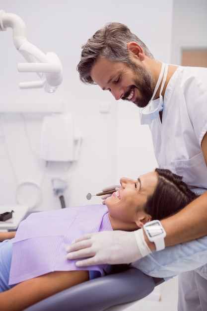 Kostenloses Foto der zahnarzt lächelt, während er den patienten untersucht