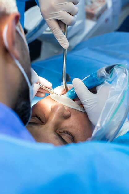 Der Zahnarzt und Assistent mit dem Werkzeug nimmt einige Manipulationen im Mund des Patienten vor