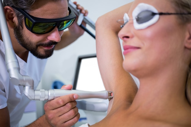 Dermatologe entfernt Haare der Achsel des Patienten