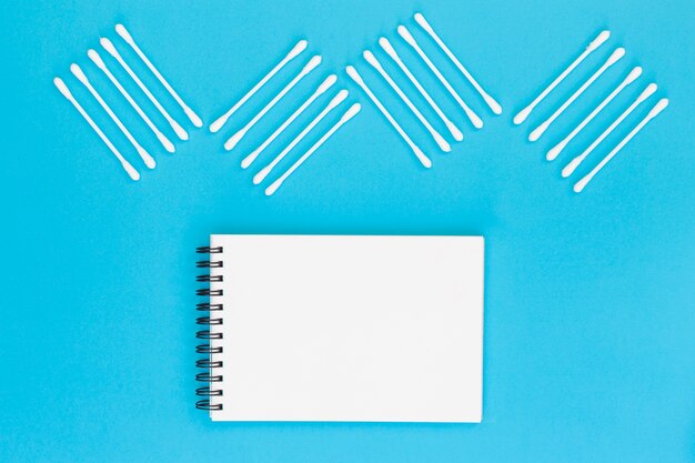 Design gemacht mit Wattestäbchen auf leerem gewundenem Notizblock auf blauem Hintergrund
