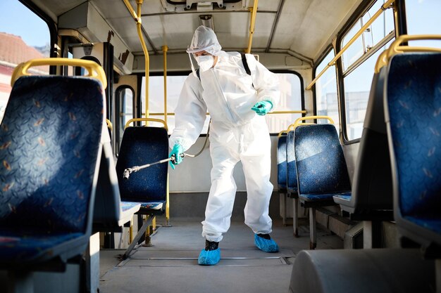 Desinfektionsmittel-Arbeiter, der aufgrund einer Coronavirus-Pandemie in einem öffentlichen Bus sprüht