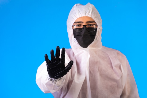 Desinfektionsmittel in spezieller vorbeugender Uniform und Masken auf Blau