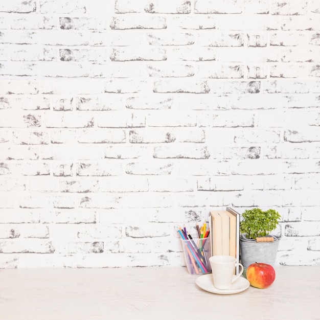 Desktop mit Büchern und Tasse in der Nähe von Wand