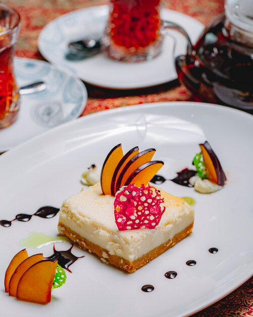 Dessert-Käsekuchen mit Seitenansicht, dekorierten Apfelscheiben und einem Glas Tee