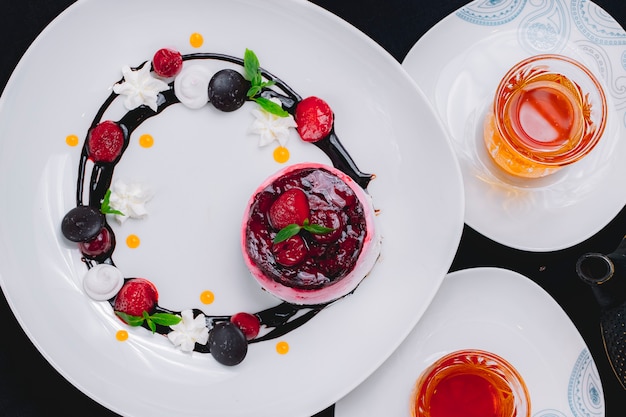 Dessert-Souffle von oben mit Erdbeergelee, dekoriert mit Schokoladenglasur und Erdbeeren und mit einer Tasse Tee