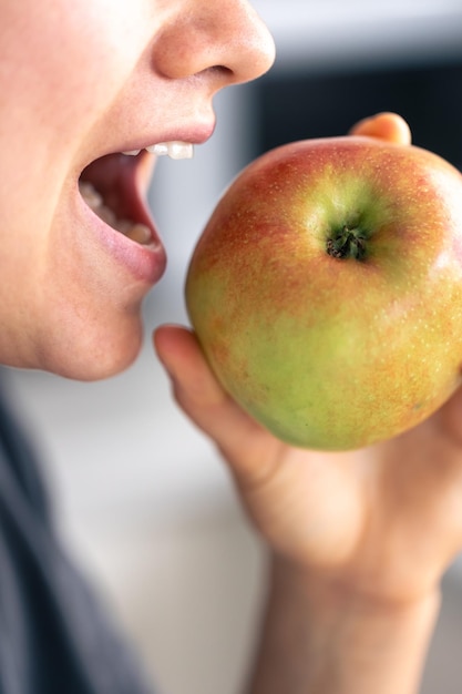 Detaillierte Aufnahme einer Frau, die einen ganzen frischen Apfel isst