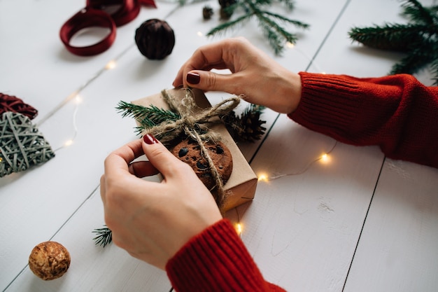 Details der Vorbereitung für Weihnachten. Frau, die ein Weihnachtsgeschenk verpackt.