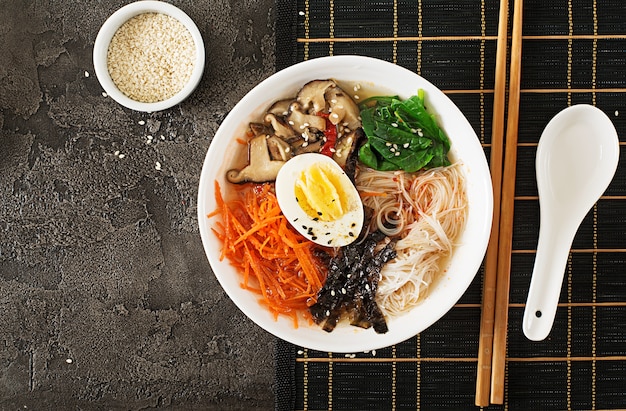 Diät vegetarische Schüssel Nudelsuppe von Shiitake-Pilzen, Karotten und gekochten Eiern. Japanisches Essen. Ansicht von oben. Flach liegen