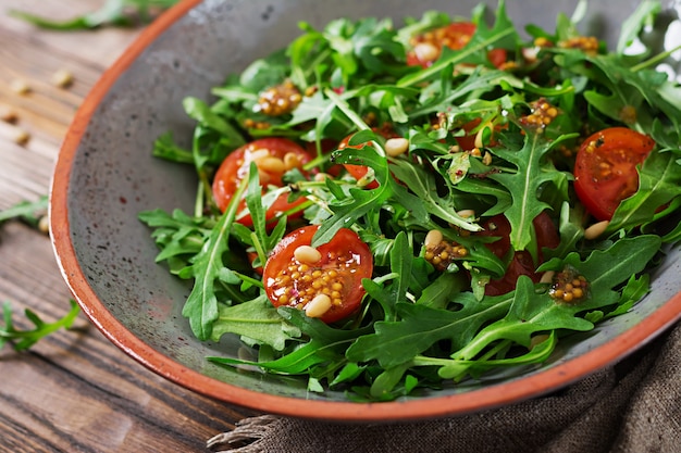 Diätmenü. Vegane Küche. Gesunder Salat mit Rucola, Tomaten und Pinienkernen.