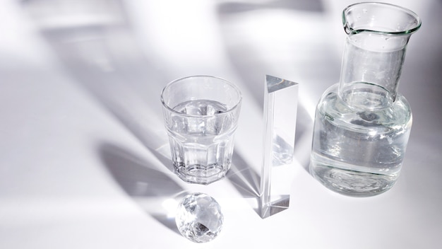 Diamant; Wasserglas; Prisma und Becherglas mit Schatten auf weißem Hintergrund