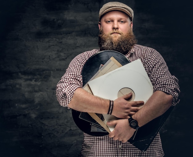 Dicker bärtiger hipster-mann hält vinyl-schallplatten.