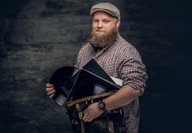 Kostenloses Foto dicker bärtiger hipster-mann hält vinyl-schallplatten.