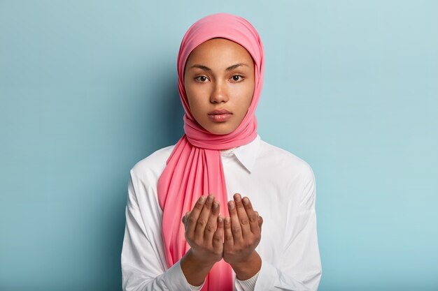 Die afrikanische muslimische Frau betet traditionell zu Gott und hält die Hände in der Gebetsgeste