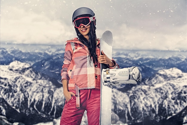 Die attraktive sportliche Frau hält Snowboard bei einer Fotosession im Hochgebirge.