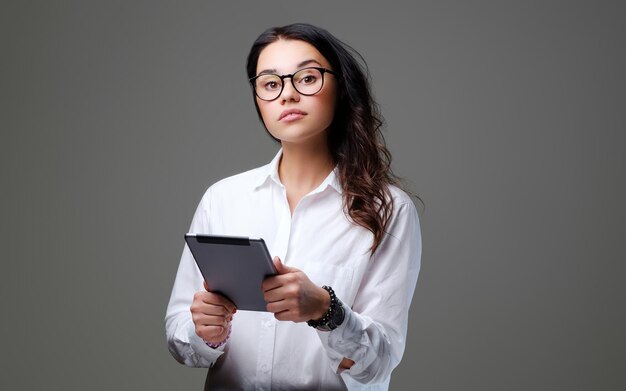 Die attraktive Studentin hält Tablet-PC. Isoliert auf grauem Hintergrund.