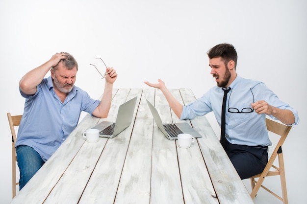 Die beiden Kollegen arbeiten zusammen im Büro an der weißen Wand