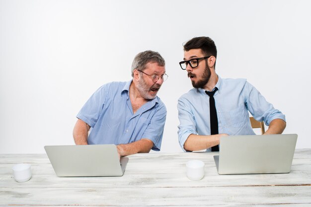 Die beiden Kollegen arbeiten zusammen im Büro an der weißen Wand