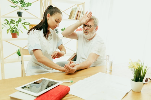 Die besuchende Krankenschwester oder der Gesundheitsbesucher, der sich um den älteren Mann kümmert