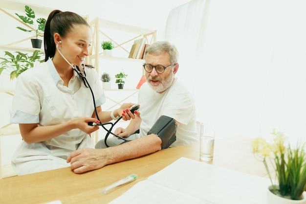 Die besuchende Krankenschwester oder der Gesundheitsbesucher, der sich um den älteren Mann kümmert