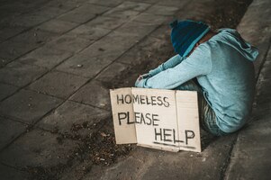 Kostenloses Foto die bettler sitzen mit einer obdachlosen nachricht unter der brücke. bitte helfen sie.