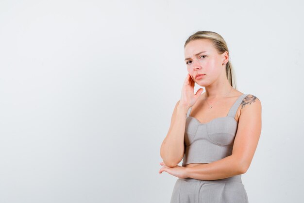 Die blonde Frau denkt, indem sie ihre Hand auf die Schläfe auf weißem Hintergrund hält