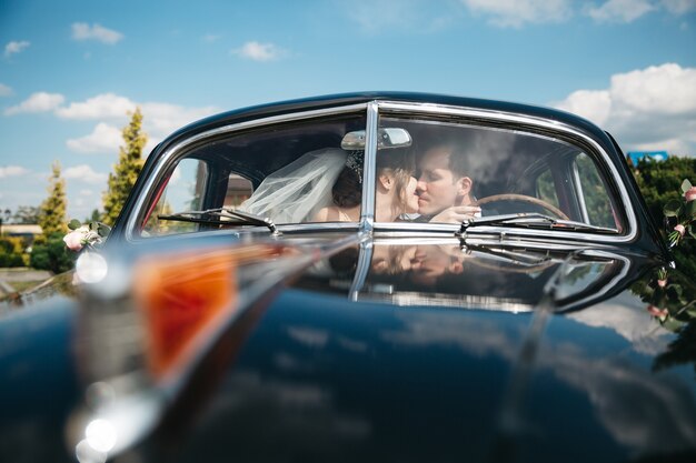 Die Bräute küssen das Auto am Hochzeitstag