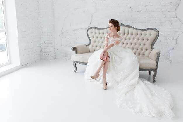 Die Braut, die aus dem Fenster schaut, wartet sie auf den Bräutigam, der auf großem klassischem Sofa sitzt.