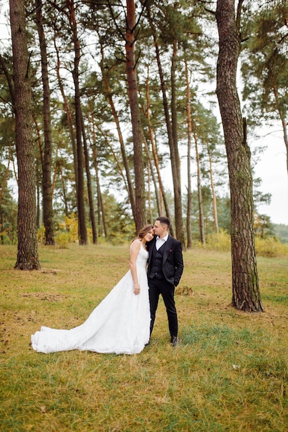 Die Braut und der Bräutigam laufen durch ein Hochzeitsfoto-Shooting im Wald