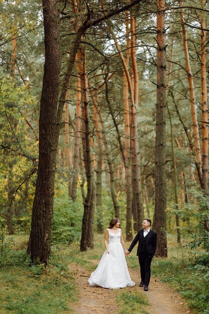 Die Braut und der Bräutigam laufen durch ein Hochzeitsfoto-Shooting im Wald