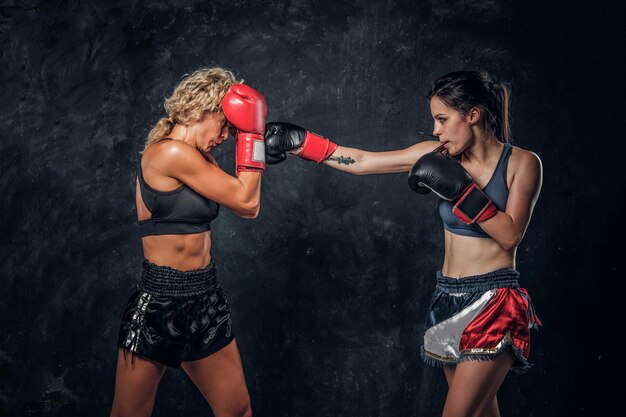 Die Erfahrungstrainerin und ihre junge Schülerin haben ein Boxtraining mit Boxhandschuhen.