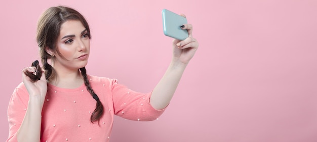 Die Frau, die ausprobiert, wirft für selfie beim Halten des Smartphone auf