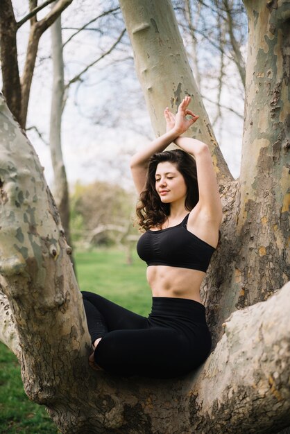 Die Frau, die Yoga im Park mit Augen tut, schloss