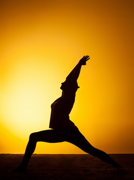 Die Frau, die Yoga im Sonnenuntergangslicht praktiziert