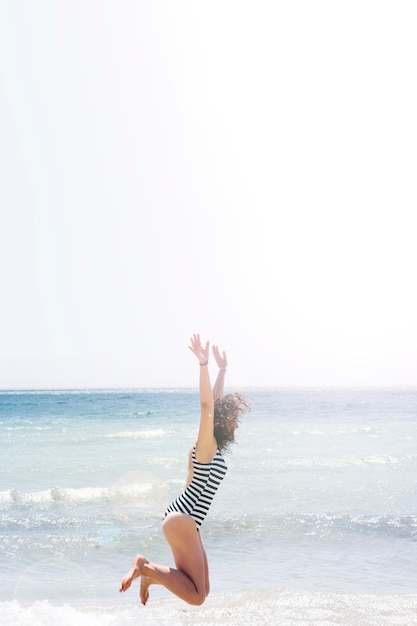 Die Frau springend in den Strand