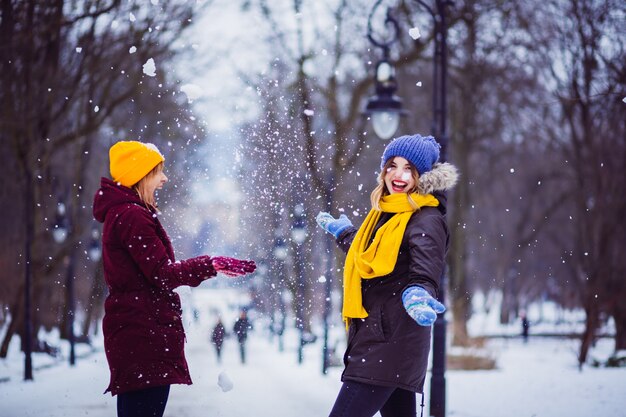 Die freundlichen Mädchen, die mit Schnee im Park spielen