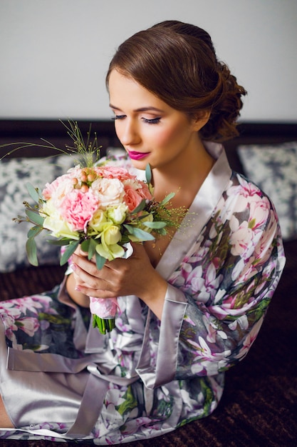 Die frisch verheiratete schöne Frau beginnt mit der Vorbereitung des Hochzeitstags im Blumenbademantel